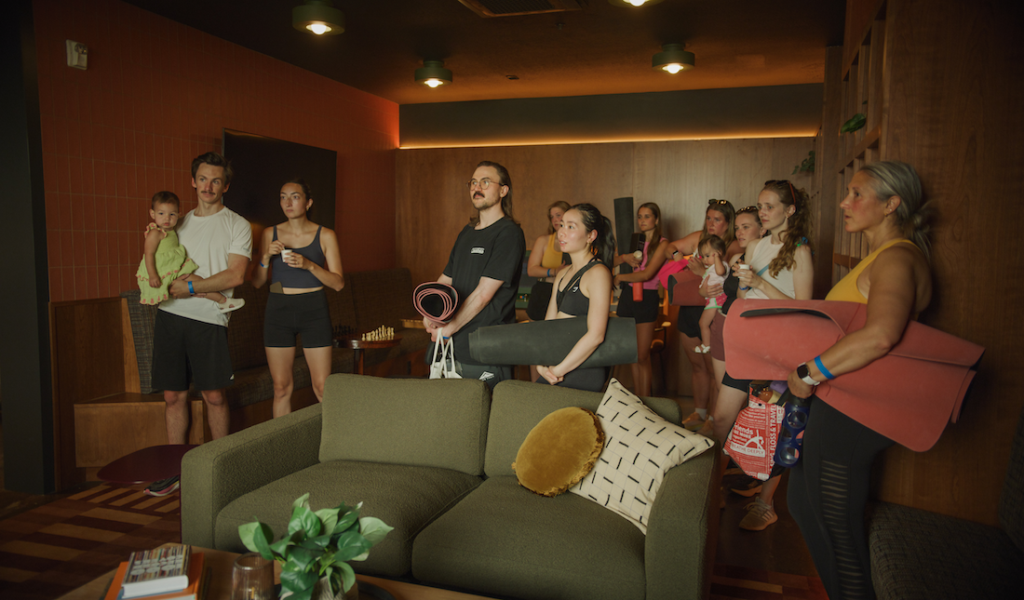 A group of people holding yoga mats, getting a tour of an Utah City residence for rent. 