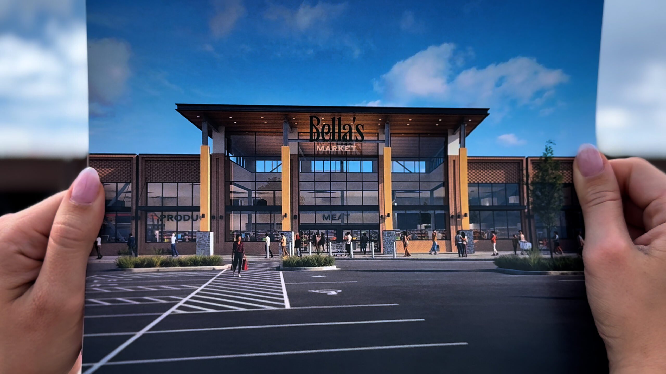 Person holding a printed photo of a rendering of Bella's Market at Utah City.